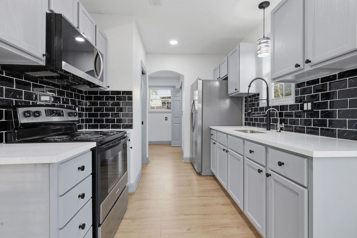 Kitchen with white cabinets and a black subway tile backsplash