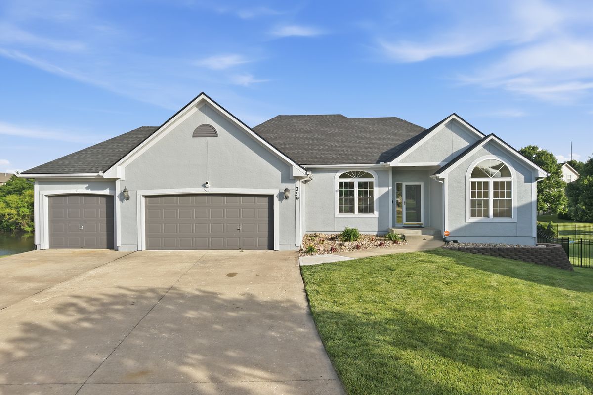Gray stucco home with a three-car garage and green lawn