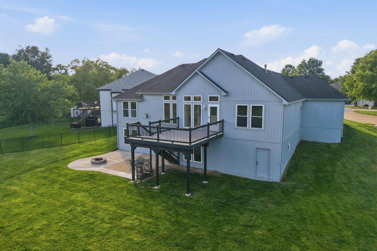 Aerial view of the back of a home with a deck and fire pit